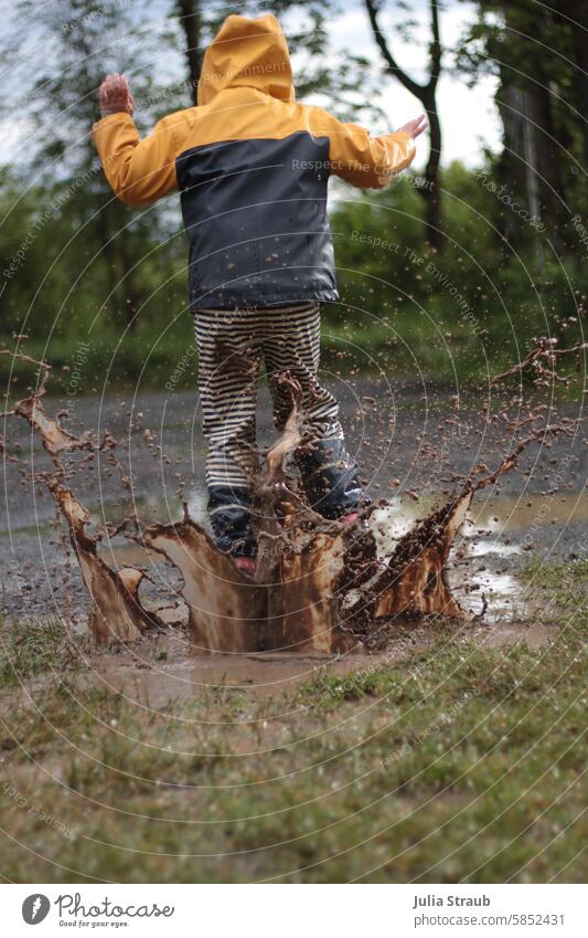 Spass in der Riesenpfütze 2 nass Sommer Schotterweg Wiese Freude spass Spaß haben draußen Planschen Gummistiefel hüpfen Regenkleider Kind matschhose Spielen