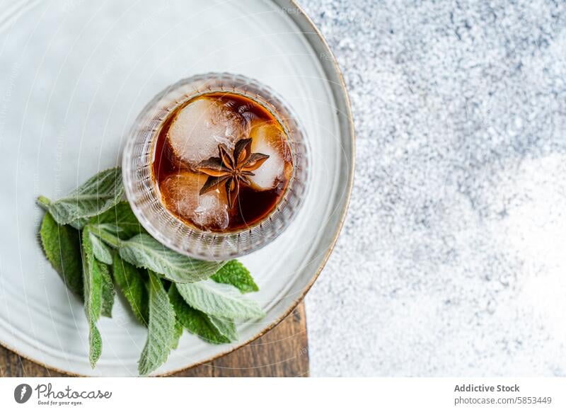 Draufsicht auf einen Kirschcocktail mit Eis und Minze auf einem Teller Getränk Cocktail Kirsche trinken rustikal Sternanis Garnierung erfrischend Sommer Alkohol