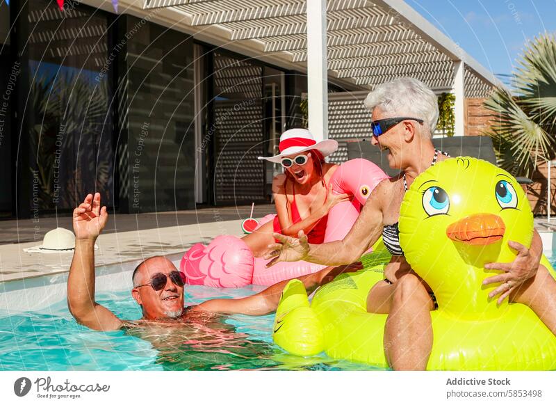 Fröhliche Senioren genießen die Zeit im Schwimmbad mit Hüpfburgen Spaß aufblasbar Ente Ring Lachen sonnig im Freien Freizeit Erholung Wasser Sommer Fröhlichkeit