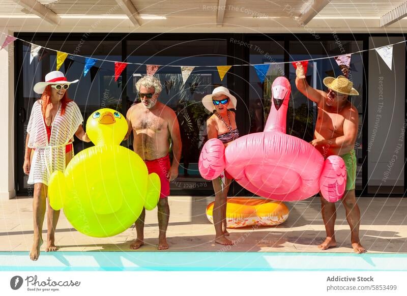 Fröhliche Senioren feiern mit Poolschwimmern Spaß Schwimmbad Party Feier Schwimmer aufblasbar Ente Flamingo Transparente festlich Freizeit Ruhestand Sommer