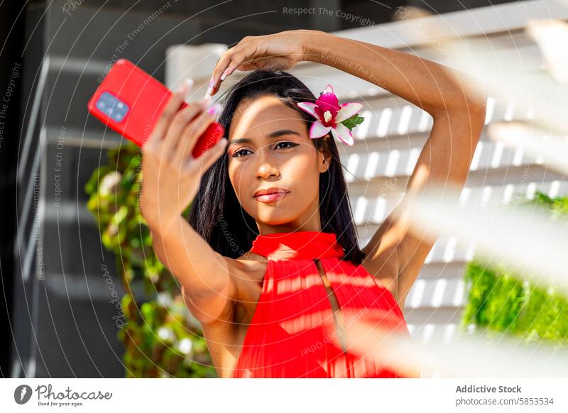 Dame in Rot fängt Selfie-Moment mit Telefon ein Frau rot Kleid Smartphone Blume Behaarung Eleganz Stil Schönheit Mode pulsierend Fotokamera posierend tropisch