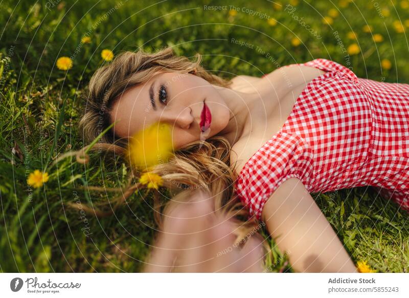 Junge Frau in einem grasbewachsenen Feld mit Blumen liegend Natur Park sich[Akk] entspannen heiter grün Gras Lächeln Ruhe sonnig Frühling im Freien Jugend