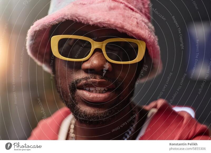 Schwarzer Mann mit Retro-Sonnenbrille und rosa Outfit Hiphop Rapper in die Kamera schauen Aufzeichnen Video Eimerhut Influencer Künstlerin soziale Netzwerke