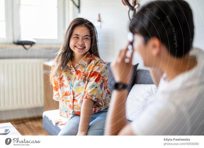 Junger Mann fotografiert seine Freundin zu Hause asiatisch echte Menschen Spaß genießend junger Erwachsener authentisch heiter selbstbewusst Frau Glück Freude