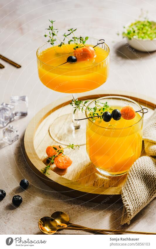 Sommer Getränke in zwei Gläser auf einem Holz Serviertablett. Erfrischungsgetränk. orange Saft Trinkglas Servierfertig Farbfoto Limonade Gesundheit gelb