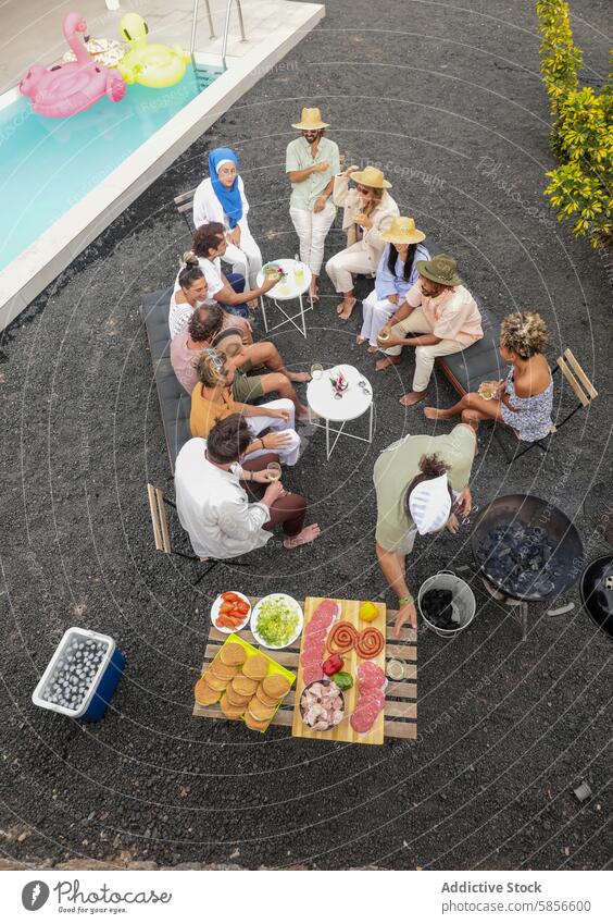 Multiethnische Freunde versammeln sich zu einer Grillparty am Pool Sommer grillen Beckenrand Sammeln im Freien Lebensmittel Gespräch Schwimmbad vielfältig