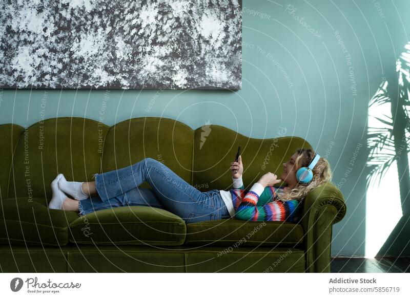 Entspannte Person, die zu Hause auf einer Couch im Internet surft einzeln Sofa Smartphone entspannt heimwärts Freizeit abstrakt Kunstwerk grün Liege digital