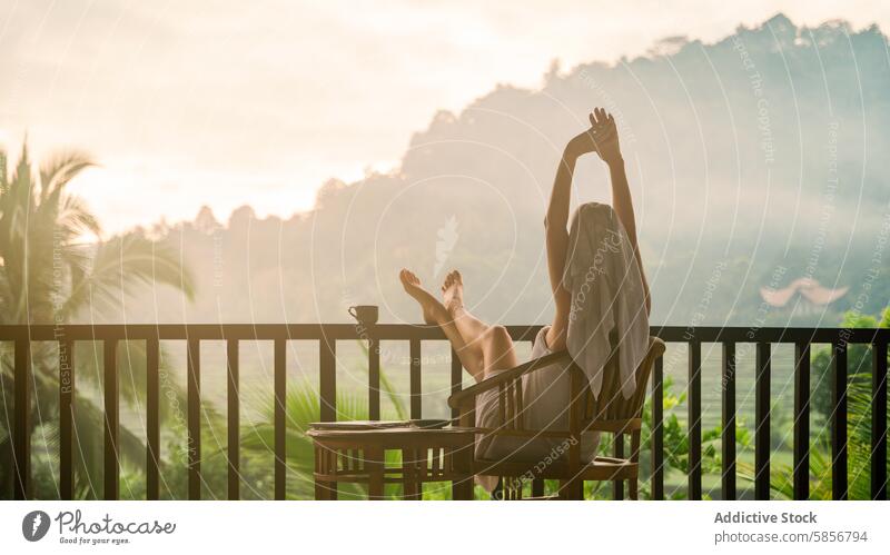 Frau genießt einen friedlichen Morgen in einer tropischen Umgebung Balkon strecken Sonnenaufgang Ruhe Verjüngung Landschaft Nebel üppig (Wuchs) entspannt