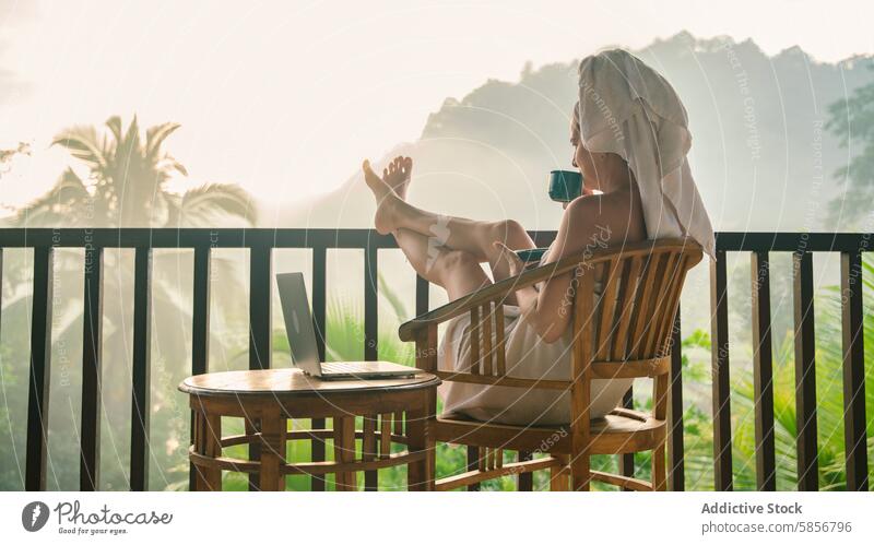 Frau entspannt mit Kaffee auf tropischem Balkon bei Sonnenaufgang Morgen entspannend Landschaft Nebel rustikal Frieden Handtuch Laptop Sitzen genießend Natur