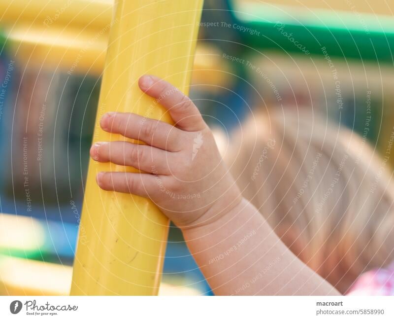 Hand eines Kleinkindes an einer gelben Stange eines Klettergerüstes kleinkind kita kindergarten kindertagesstätte finger fingerche mädchen kindlich niedlich