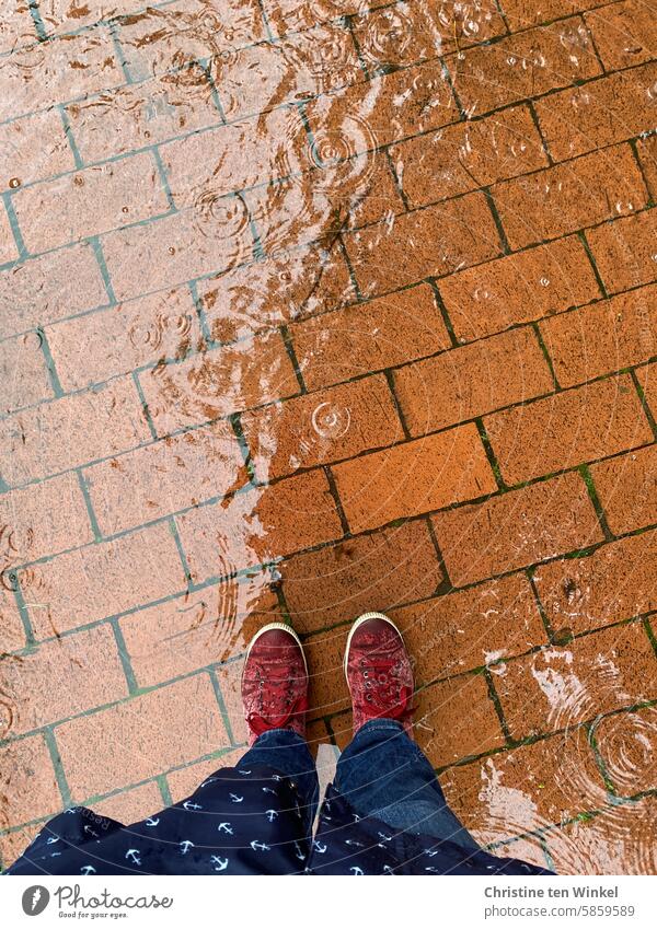 bei Regenwetter zu Fuß unterwegs Pfütze nass nasse Schuhe Regenmantel Regentropfen schlechtes Wetter Reflexion & Spiegelung Gehweg Pflastersteine gepflastert