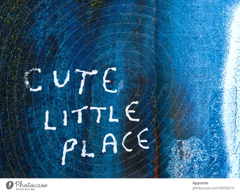 "Cute little place" - Handgeschriebener, dreizeiliger Schriftzug in weißen Großbuchstaben auf tiefblauem metallischen Untergrund mit Spuren von Rost und weißer Farbe