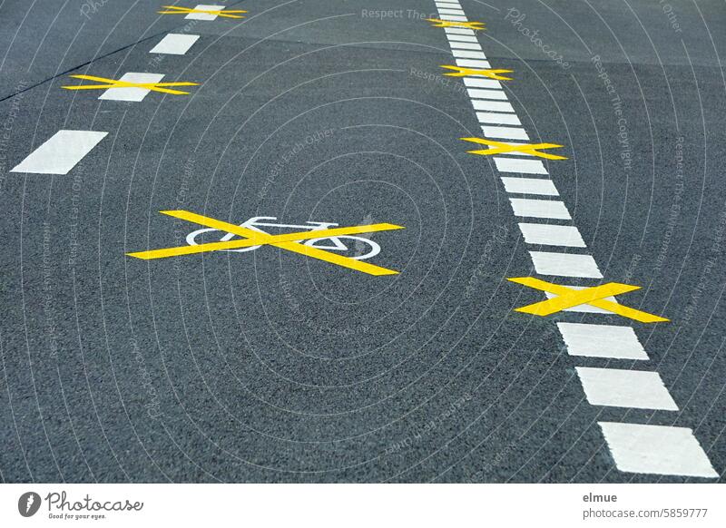 neuer, mit gelben Kreuzen noch ungültig gemachter Fahrradweg auf einer Asphaltstraße Radpiktogramm Radweg Fahrbahnmarkierung StVO Piktogramm Straßenmarkierung