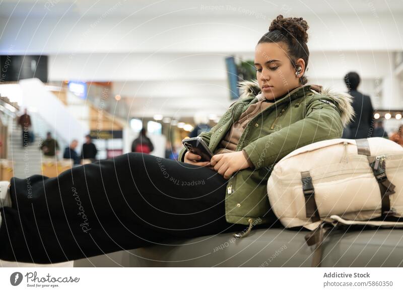Junge Frau benutzt Smartphone am Flughafen jung Warten reisen Sitzen Technik & Technologie Passagier Mitteilung Handy Terminal Reise Transport im Innenbereich