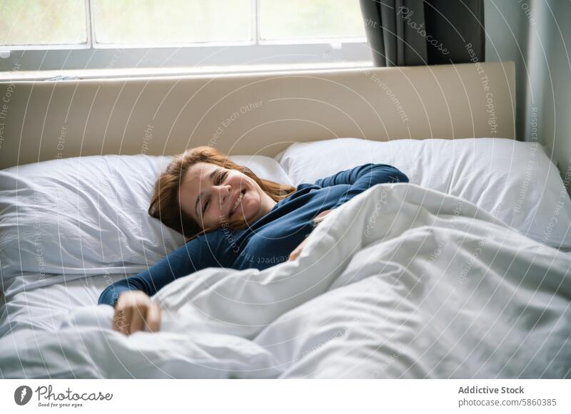 Die morgendliche Freude einer Frau, die sich im Bett entspannt Lächeln entspannend Schlafzimmer Komfort gemütlich Tageslicht Fenster Morgen Laken Kopfkissen