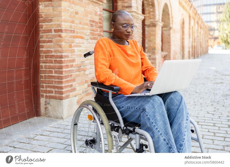 Afroamerikanische Frau im Rollstuhl arbeitet im Freien an einem Laptop Business Afroamerikaner schwarz ethnisch Zugänglichkeit Einschluss Arbeit Straße Baustein