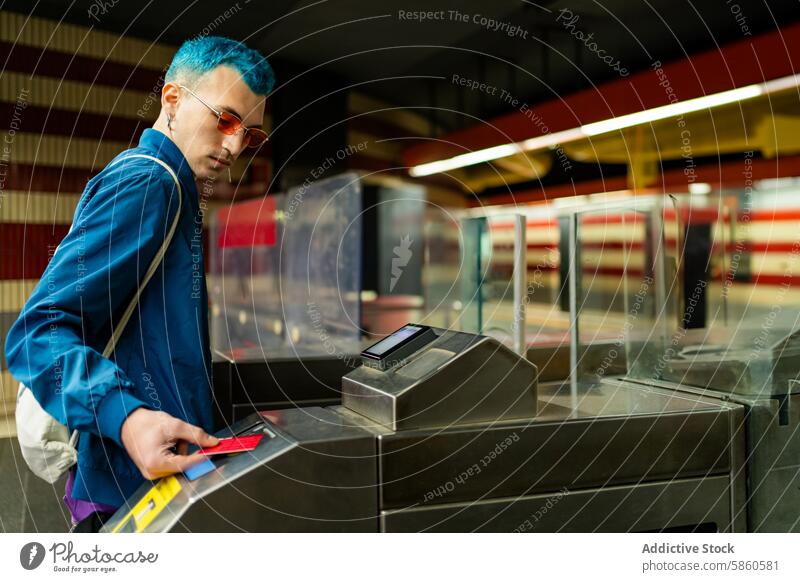 Mann mit blauem Haar beim Betreten eines Drehkreuzes in einer U-Bahn-Station blaue Haare Fahrkarte Stil Sonnenbrille lässig Jacke jung Mode Zugänglichkeit