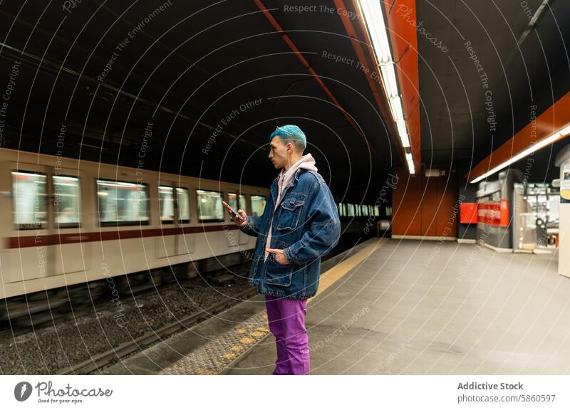 Junger Mann mit blauem Haar wartet auf den Zug und telefoniert U-Bahn Podest Telefon Transport urban Arbeitsweg Warten blaue Haare Jacke Stehen