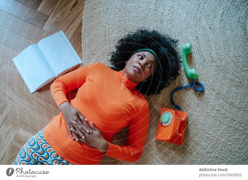 Frau in Orange mit Vintage-Telefon schaut weg schwarz orange Pullover Rock Stock altehrwürdig grün Wegsehen Teppich Holz retro Bauch Konzept Hausfrau 50s Mode