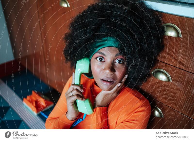 Überrascht Black African American Frau spricht auf Retro-Telefon in Vintage-Stil Küche schwarz Afro-Look überrascht retro altehrwürdig 1950s orange grün