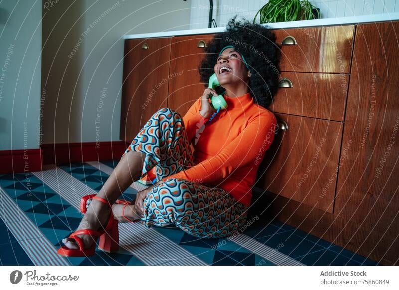 Retro-Hausfrau, die in einer bunten 50er-Jahre-Küche am Telefon plaudert Frau Afro-Look plaudernd rotierend Stock Sitzen 1950s retro altehrwürdig farbenfroh