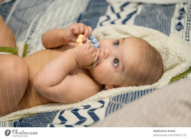 Baby spielt mit bunten Perlen auf weicher Decke spielen farbenfroh Silikon gemütlich Säugling Kind Starrer Blick Wegsehen liegend blau grau weiß spielerisch