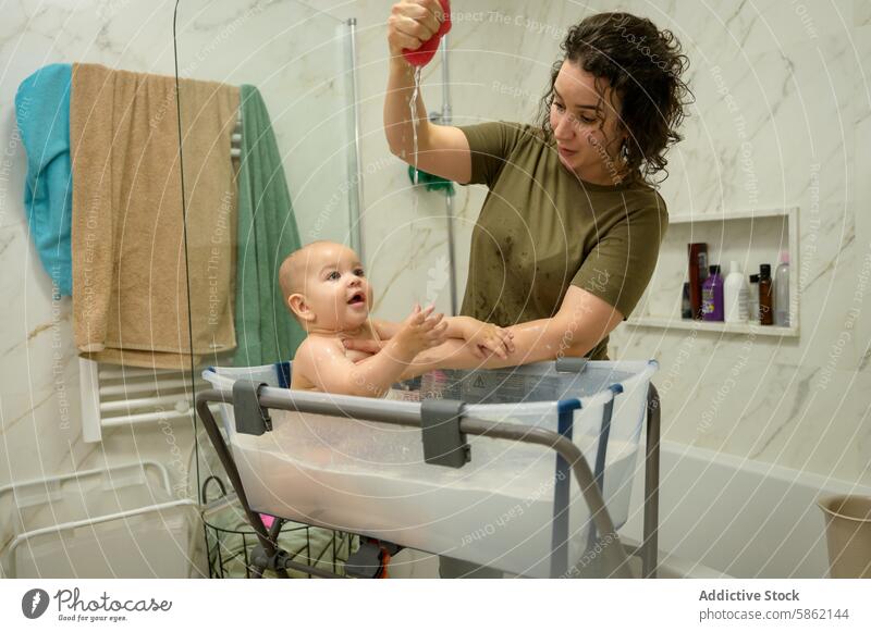 Fröhliches Babybad mit Mama in einem modernen Badezimmer Mutter Wasser Spielzeug Lächeln Kaukasier Säugling Glück spielerisch Pflege Mutterschaft