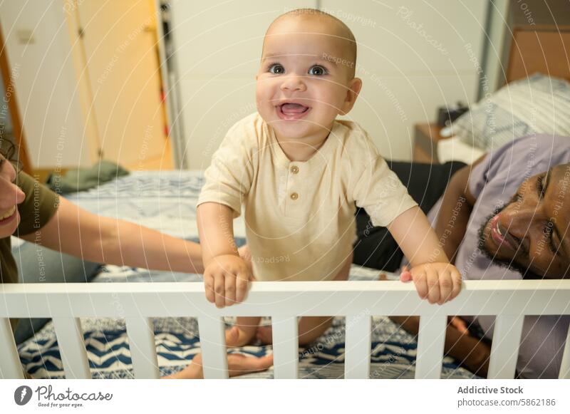 Eine gemischtrassige Familie genießt die Zeit mit ihrem freudigen Baby rassenübergreifend multiethnisch Afroamerikaner Kaukasier Babybett Lächeln heimwärts