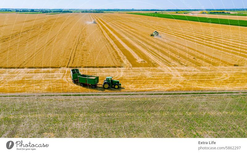 Blick von oben auf den Mähdrescher, der Traktor wartet auf den Umschlag, während die Erntemaschine Weizen erntet Antenne Ackerbau Müsli Land Bodenbearbeitung