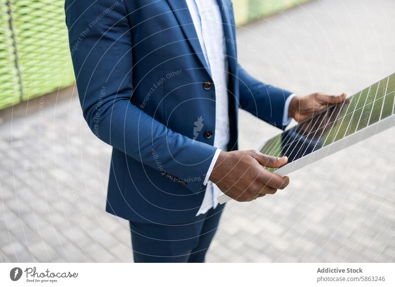 Schwarzer Geschäftsmann begutachtet Solarpanel im Freien schwarz Sonnenkollektor Erneuerbare Energie Innovation Anzug blau formal Beteiligung