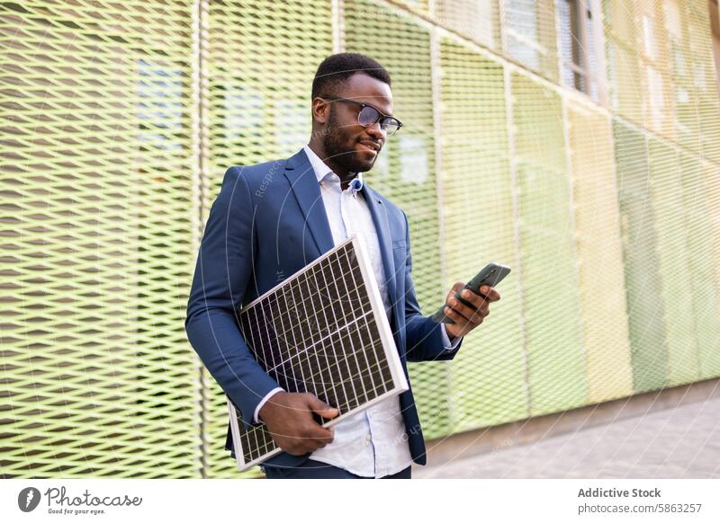 Schwarzer Geschäftsmann mit Solarpanel, der sein Smartphone im Freien benutzt Sonnenkollektor Technik & Technologie Mann Erneuerbare Energie Anzug professionell