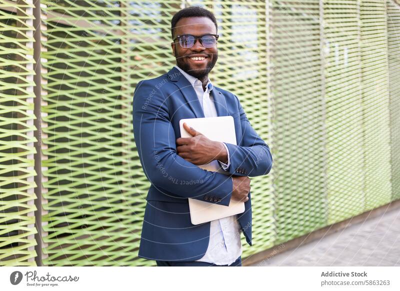 Selbstbewusster afroamerikanischer Geschäftsmann mit Laptop Mann Afroamerikaner Lächeln in die Kamera schauen blauer Anzug selbstbewusst stylisch männlich