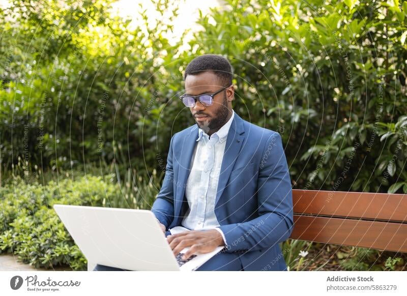 Geschäftsmann arbeitet an einem Laptop in einer Parkanlage Mann Bank Afroamerikaner professionell männlich Business Fernarbeit Technik & Technologie im Freien