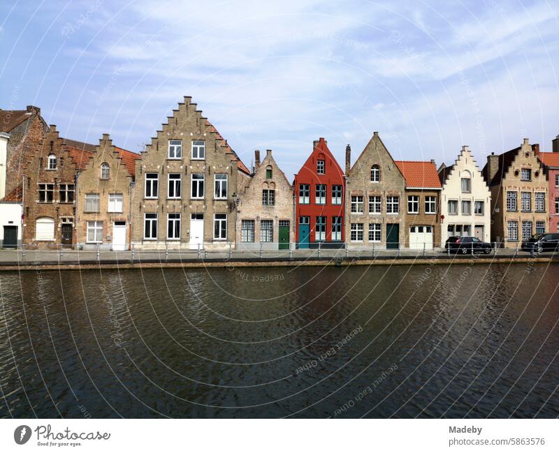 Prachtvoll restaurierte Fassaden alter Häuser mit Spitzgiebel und Treppengiebel am Kanal vor blauem Himmel im Sonnenschein in der Altstadt von Brügge in Westflandern in Belgien