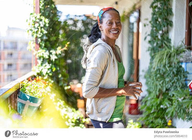 Porträt einer lächelnden Frau, die zu Hause auf dem Balkon steht Menschen Freude schwarz natürlich attraktiv schwarze Frau Fröhlichkeit Glück echte Menschen
