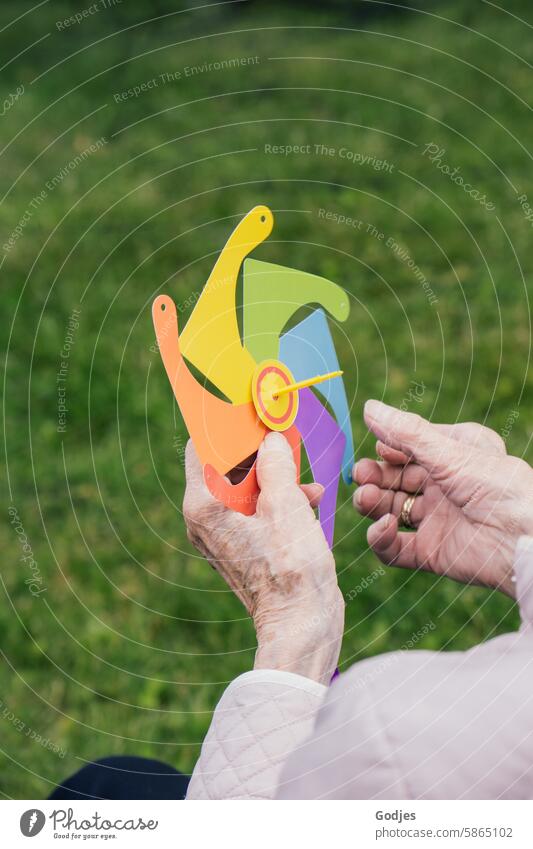 Bastelutensilien für ein Windrad in den Händen einer Seniorin Basteln bunt basteln Freizeit & Hobby mehrfarbig Papier Spielen Nahaufnahme Kindheit Kreativität
