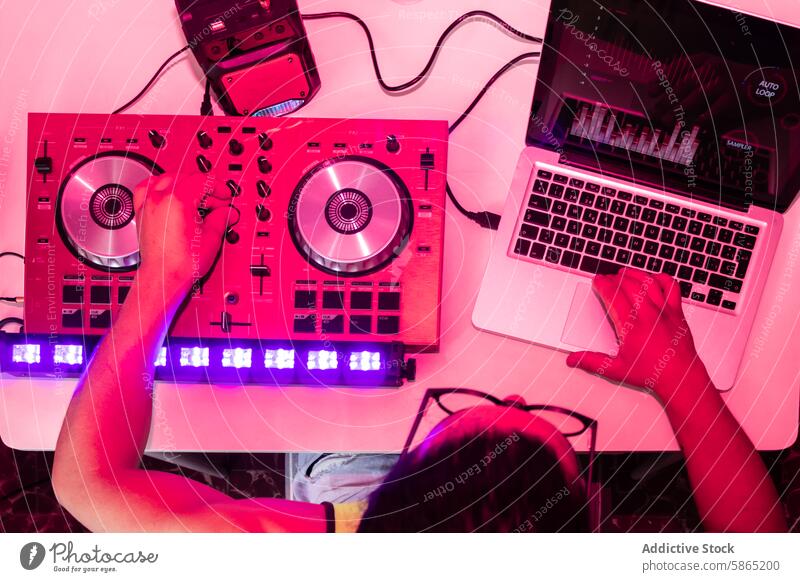 DJ mischt Tracks auf modernem Equipment unter rosa Lichtern dj Musik mischen Bahn Regler Laptop Nachtclub Hand Gerät Scheibe Jockey Plattenteller Knauf