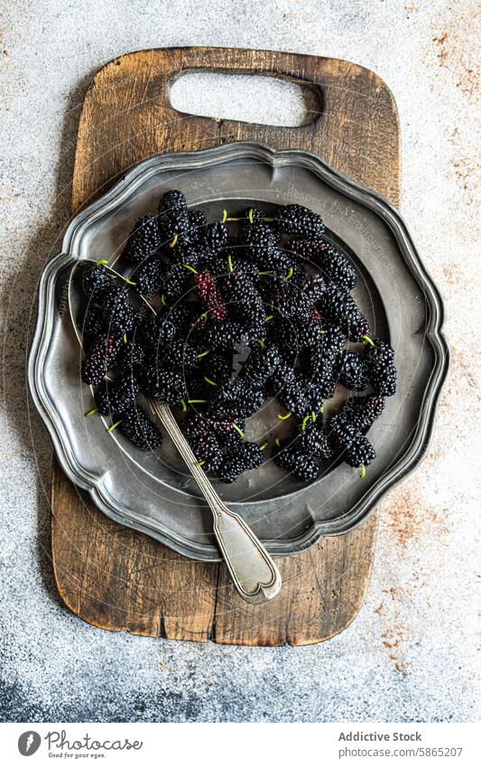 Frische Maulbeeren in einem Vintage-Metalltablett auf einem rustikalen Holzbrett Frucht Tablett altehrwürdig hölzern Holzplatte frisch saftig texturiert Silber