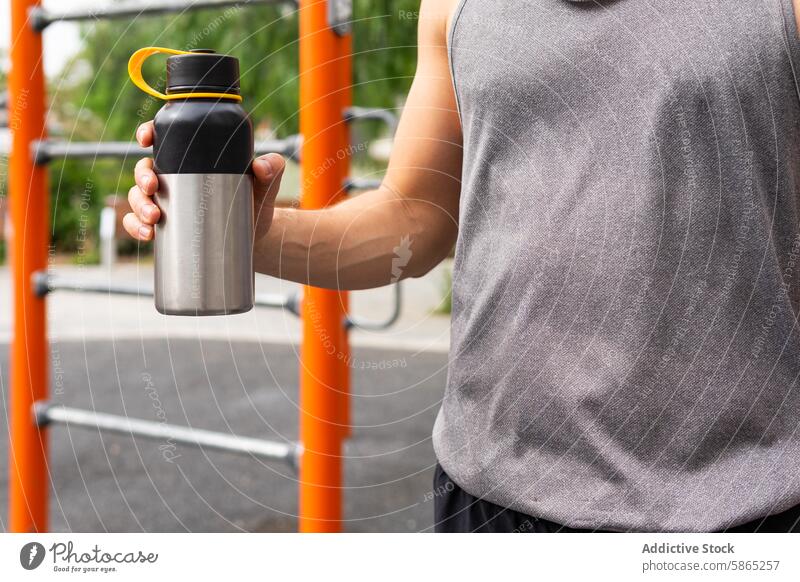 Unbekannter Mann mit einer Metallwasserflasche in einem Fitnesspark Wasserflasche Gesunder Lebensstil im Freien poblenou aktiv Stahl rostfrei Tanktop Griff