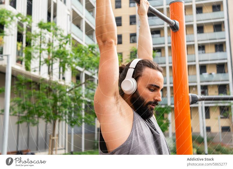 Junger Mann trainiert in einem Fitnessstudio im Freien in Poblenou jung Training poblenou urban Park Vollbart Kopfhörer Übung Sport Lifestyle lässig Kleidung