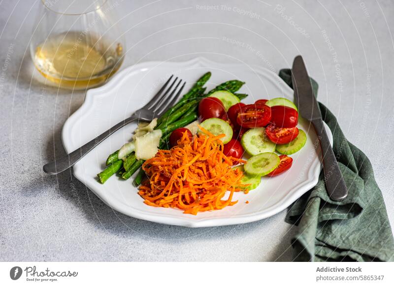 Frischer Gemüsesalat mit Spargel und geriebener Karotte Salatbeilage Käse Tomate Salatgurke Möhre Teller Gesundheit Mahlzeit frisch Dressing Besteck weiß