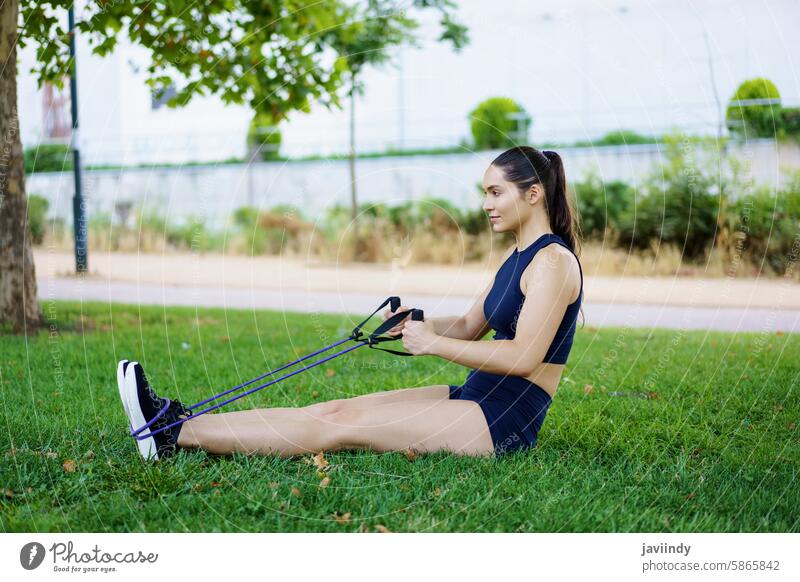 Eine junge Frau trainiert im Park mit Widerstandsbändern und zeigt damit ihre Entschlossenheit und ihr Engagement für Fitness aktiv Sportkleidung Aerobic Athlet