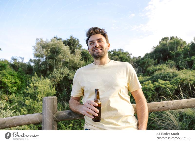 Mann genießt Bier im Freien in der Natur Zaun Lächeln jung männlich Erwachsener Getränk Alkohol lässig Hemd Sommer Tag Glück Freizeit Lifestyle entspannend