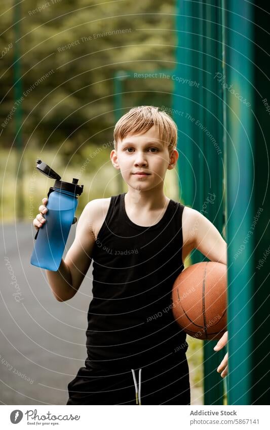 Junger Junge mit Basketball und Wasserflasche auf einem Platz im Freien Teenager Gericht jung sportlich Spiel Sommer Jugend Athlet aktiv Erholung Spielplatz