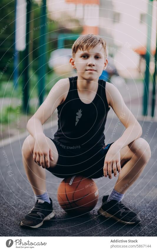 Teenager macht eine Pause vom Basketballspielen im Freien Sport aktiv jung männlich Park Sitzen fokussiert sportlich Fitness Jugend Erholung lässig Sommer