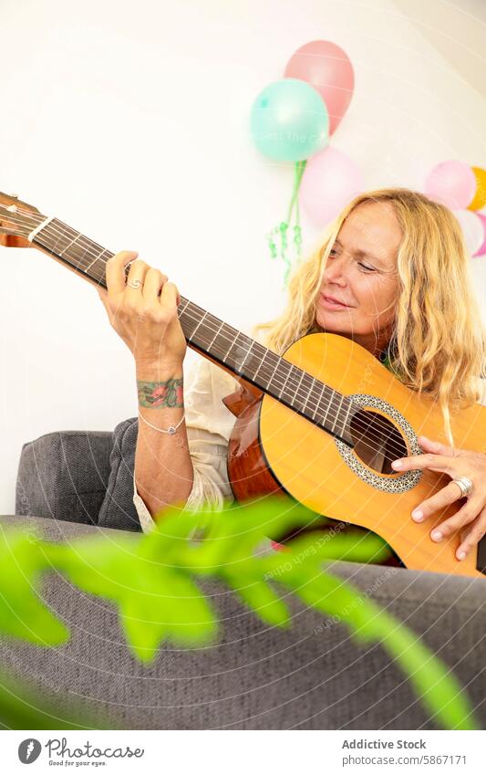 Ältere Frau genießt Gitarrenmusik bei einer bunten Feier im Haus Senior Musik Luftballon Freude Fröhlichkeit Party im Innenbereich Festlichkeit lässig Spaß