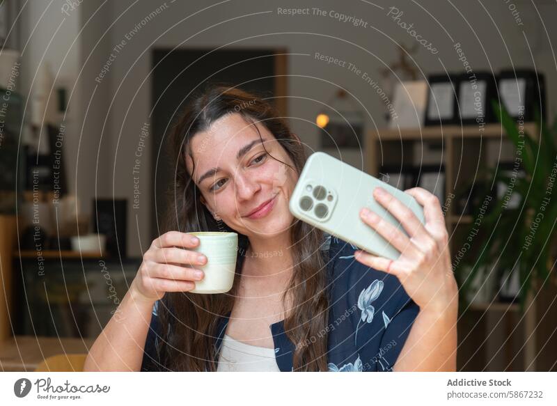 Frau genießt Kaffee, während sie ein Selfie mit ihrem Smartphone macht Kaffeepause Fotokamera Lächeln trinken Technik & Technologie Apparatur Handy lässig