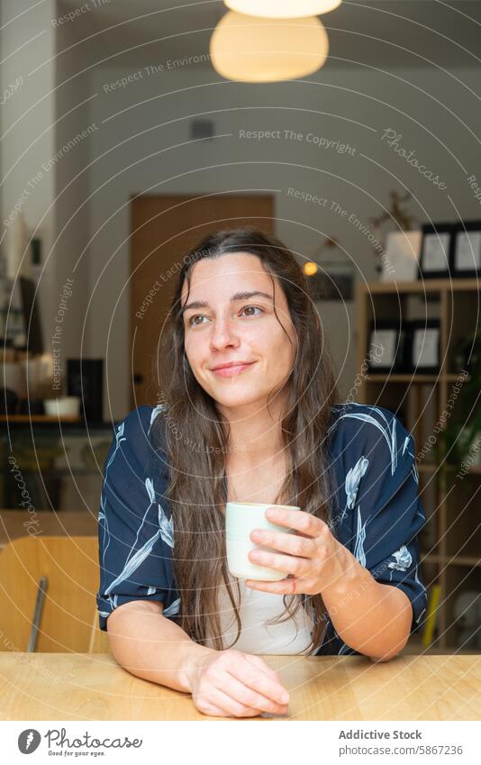 Frau genießt eine Kaffeepause in einem modernen Café Pause Wegsehen Tasse lässig geblümt Bluse Erholung nachdenklich hell im Innenbereich Sitzen Tisch trinken