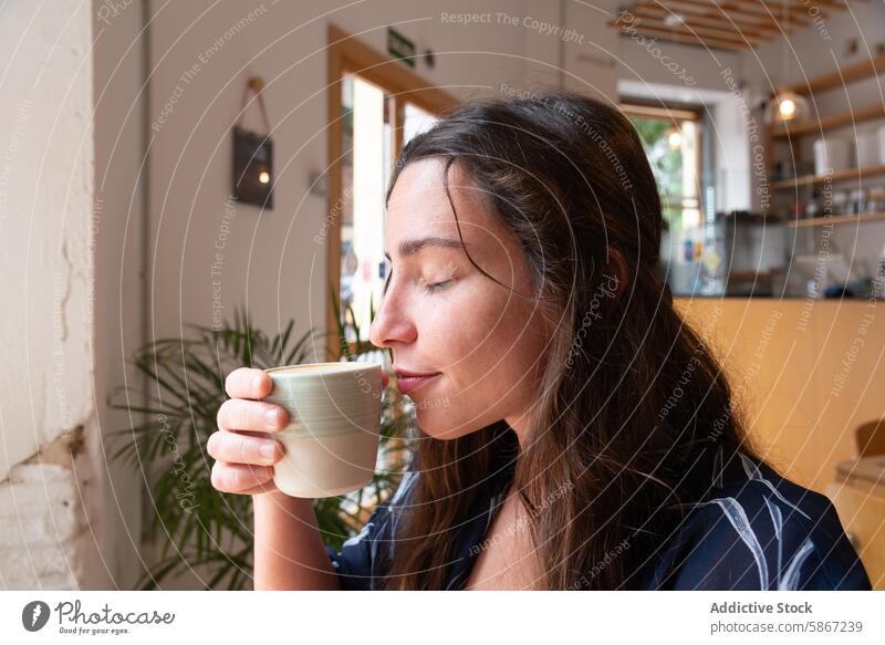 Junge Frau genießt Kaffee in einem gemütlichen Cafe Café Tasse trinken Keramik sich[Akk] entspannen Sonnenlicht Morgen schlürfend lässig Erfrischung Getränk