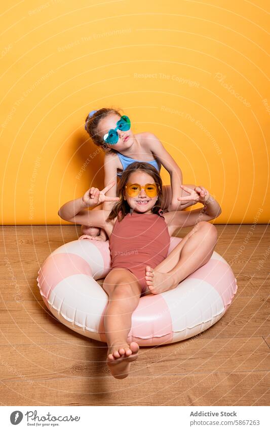 Zwei Kinder posieren in einer sommerlichen Studioeinrichtung Atelier Sommer Thema Pose spielerisch gelb Hintergrund Outfit Sonnenbrille farbenfroh aufblasbar